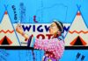 Gallery Art Shows Coming to Northern New Mexico Fall 2026 A native person in long pink robes in front of a blue background with tent illustrations.