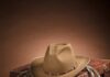 Santa Fe Home and Fashion Finds in Warm Neutrals A brown background with a whip on a brown box and a cowboy hat.