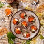 Blue corn blinis topped with crème fraîche, smoked salmon roses, salmon roe, and fresh dill sprigs, served alongside glasses of Gruet Brut Rosé sparkling wine.