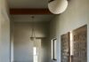 Chandler Prewitt Design Crafts a Contemporary Family-Centered Santa Fe Home An entryway with large wooden carved doors and a clean, minimalist hallway with warm white lights hanging from the ceiling.