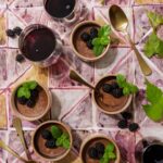 Rich dark chocolate pots de crème served in ceramic ramekins, topped with fresh blackberries and mint sprigs, paired with glasses of Janus Pinot Noir.
