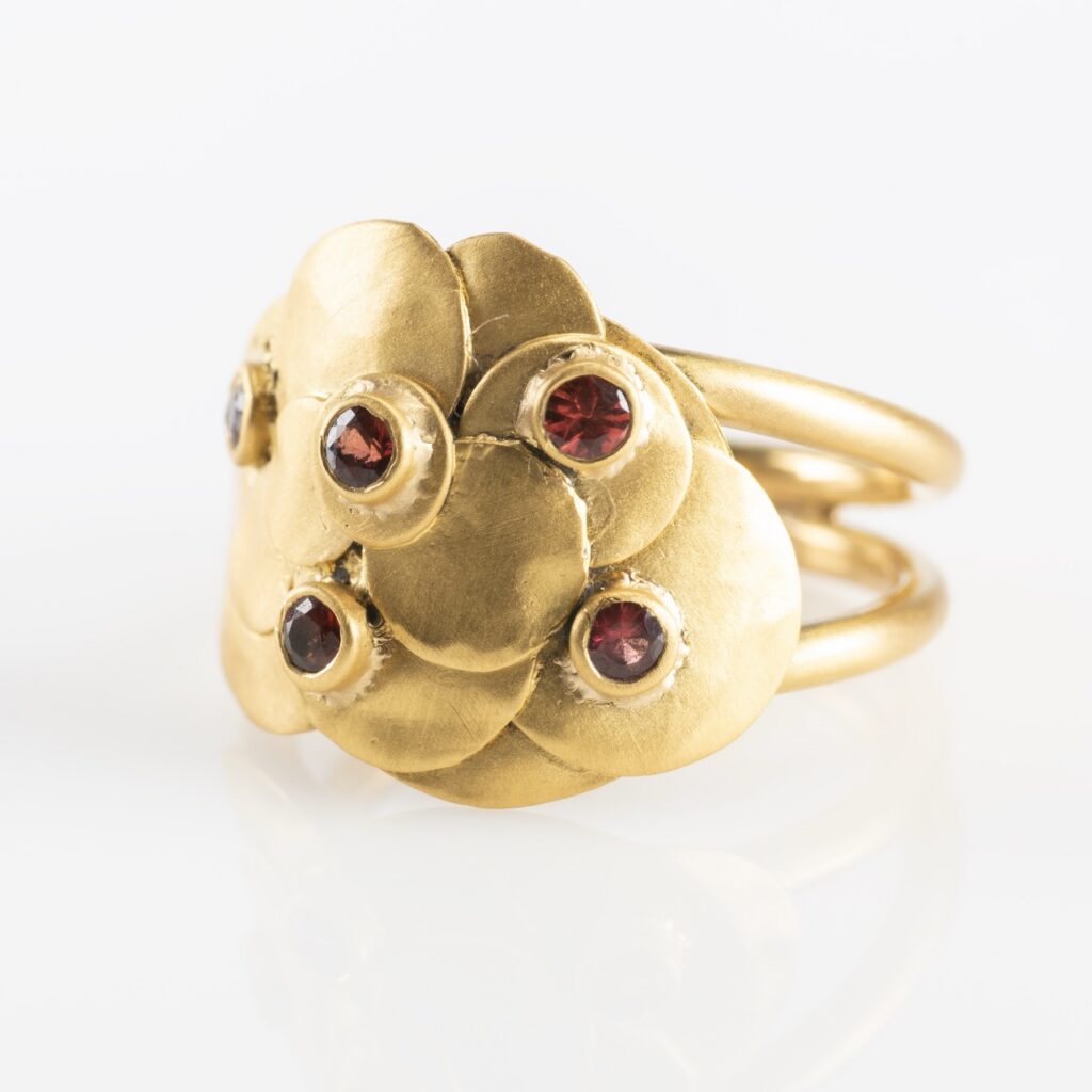 A gold flower ring with red gemstones.