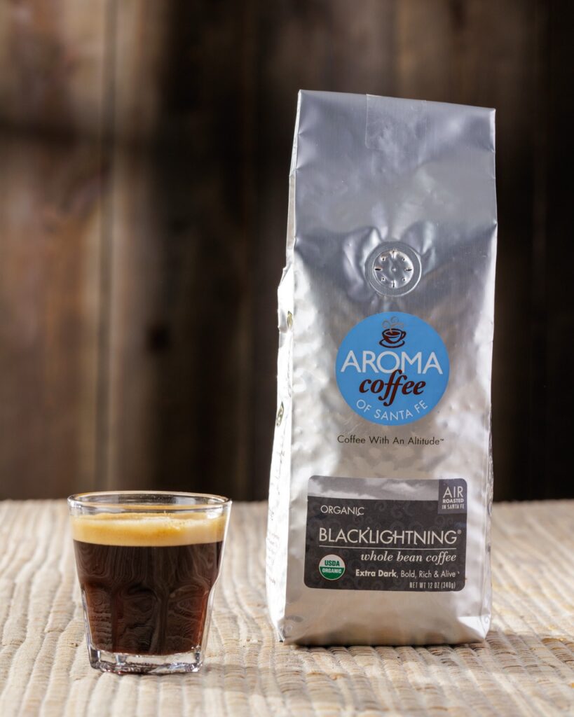 A bag of silver coffee beside a small cup of espresso.