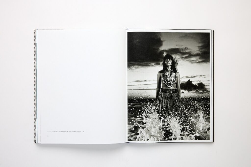 Open fine art book by Radius Books displaying a portrait photograph of a woman standing in ocean waves.