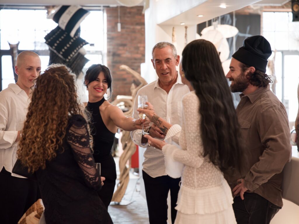 Guests raising champagne flutes for a toast while gathered in the gallery space.