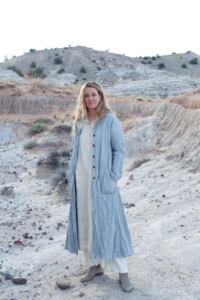 A woman in a long blue cardigan in a dessert.