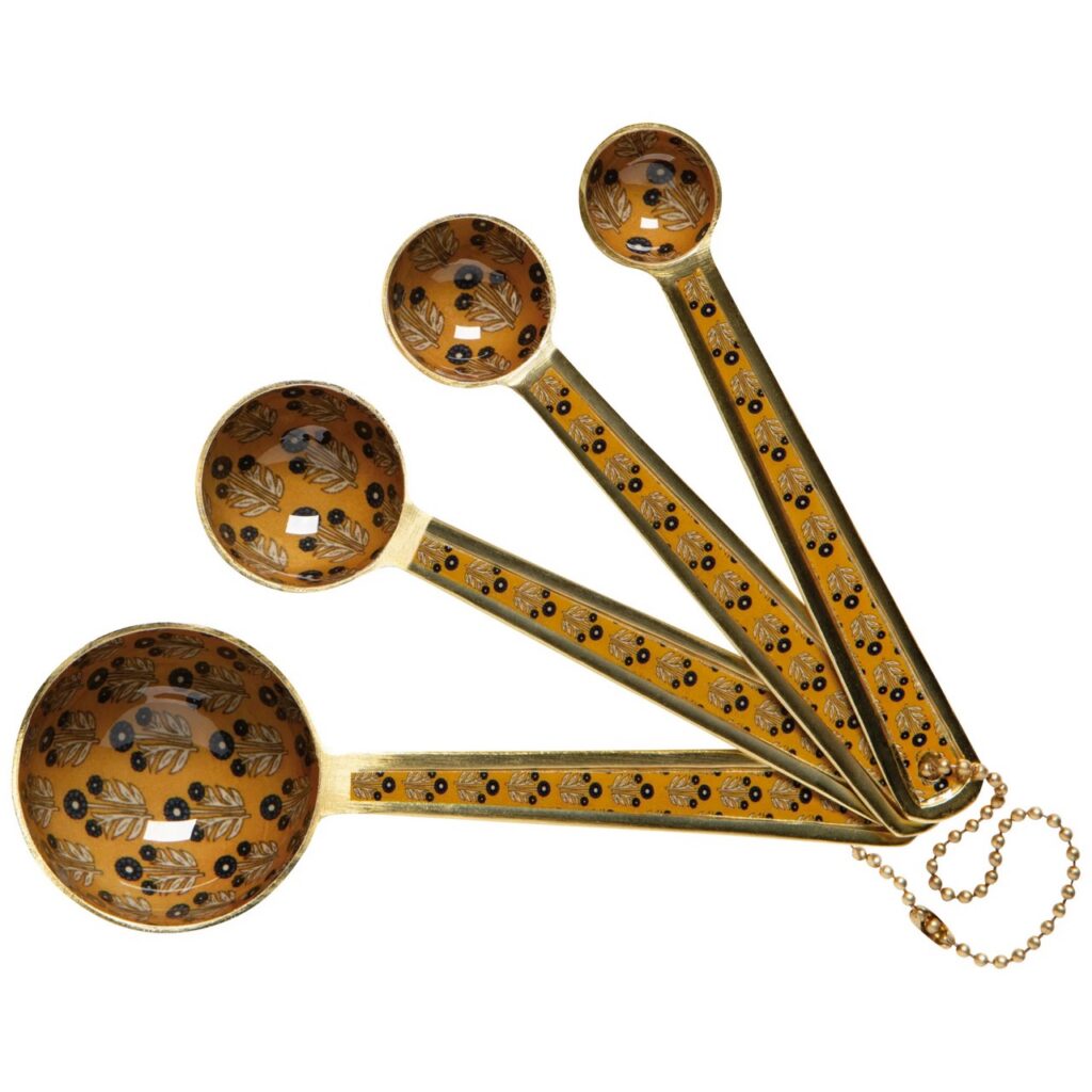 A set of four measuring spoons in a mustard yellow color with a pattern on them.