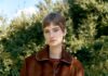 Shop Local, Glow Bold: This Week’s SOURCE Picks from New Mexico Shops and Makers A woman with short brown hair wearing a brown bomber jacket and white skirt outside.
