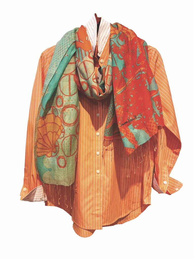 An orange blouse with a multicolored scarf around the neck.